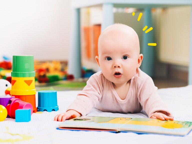 baby laying on stomach with book and toys