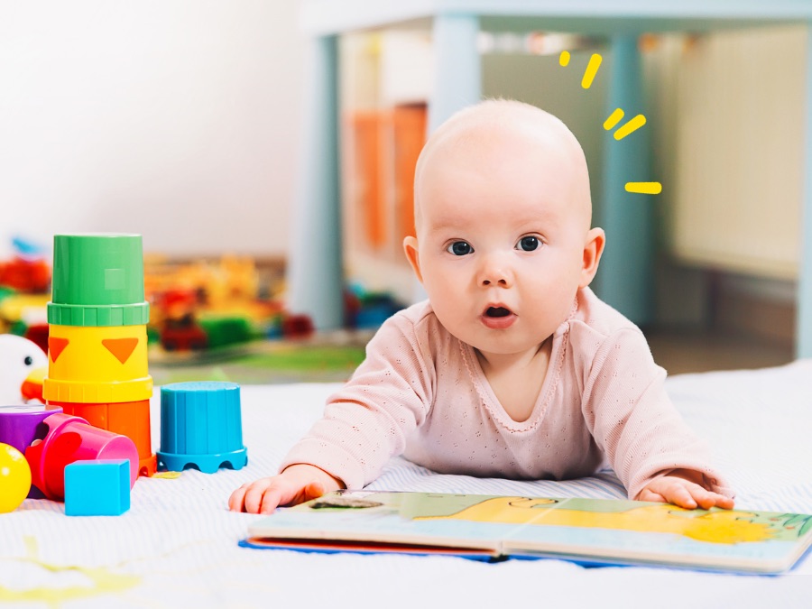 baby laying on stomach with book and toys